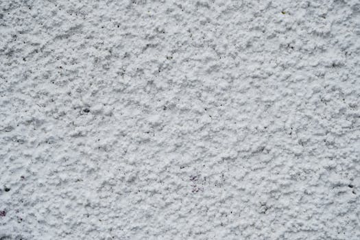 Textured white wall of old concrete building on street of town in daytime